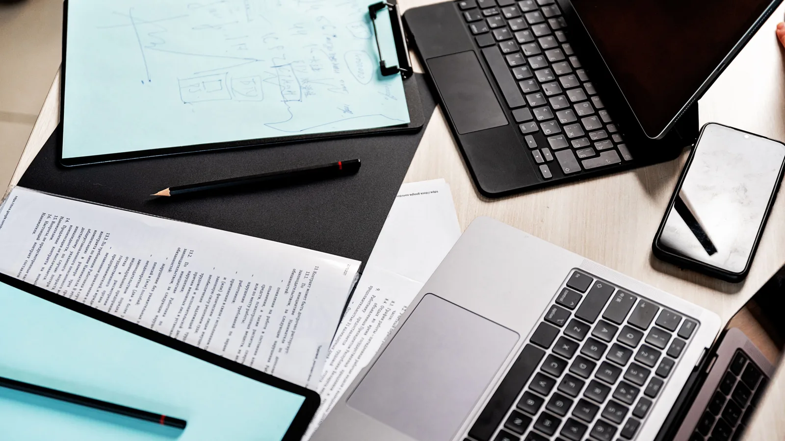 Mesa de trabajo con contratos impresos, portafolios, portátil y tableta
