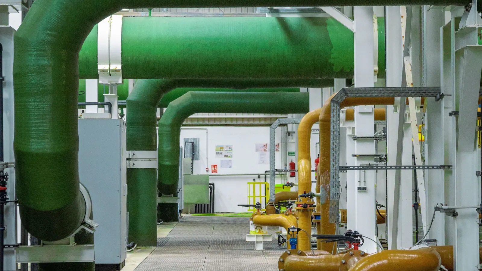 Sala de máquinas con tuberías de gran diámetro, bandejas de cables y estructura metálica